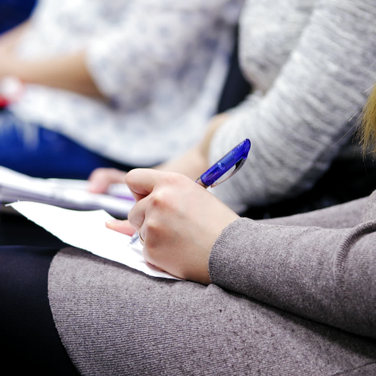 Close-up of female's hands holding pens and making notes at the conference. Woman is writing with a pen during the congress meeting.