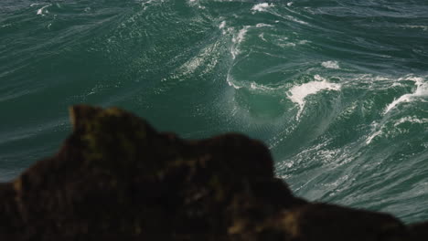 stormy wave breaking in slow motion close to rocks