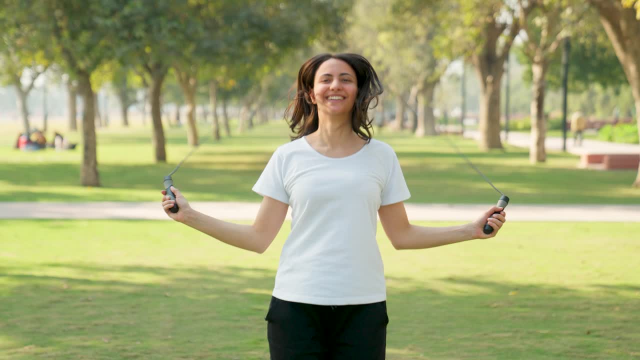 mujer india saltando la cuerda en un parque por la mañana