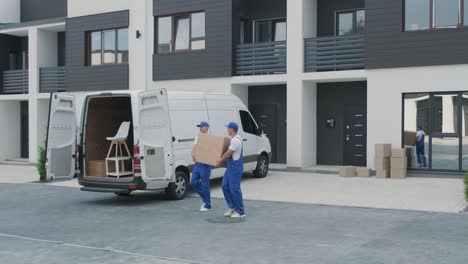 two young workers of removal company are loading boxes and furniture into a minibus