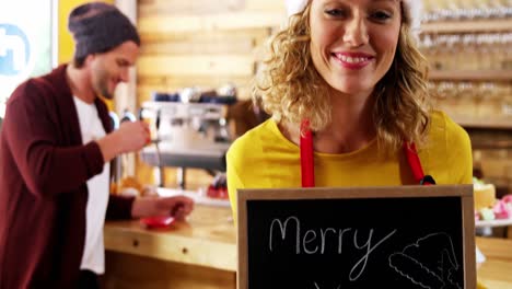 Portrait-of-waitress-showing-slate-with-merry-x-mas-sign