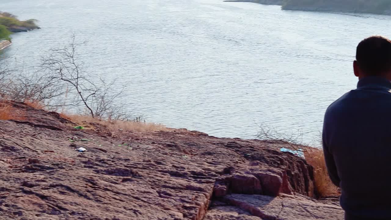 인도 카일라나 호수 조드푸르 라자스탄 인도에서 평평한 각도에서 호수 전망을 감상할 수 있는 산꼭대기에 앉아 있는 고립된 남자