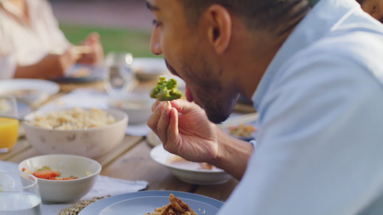 un hombre asiático comiendo una comida con su familia usando