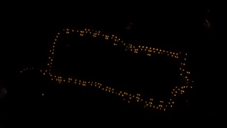 circular rotation of the drone upwards over the illuminated town where only the silhouette and perimeter of the city and behind the lighting are visible