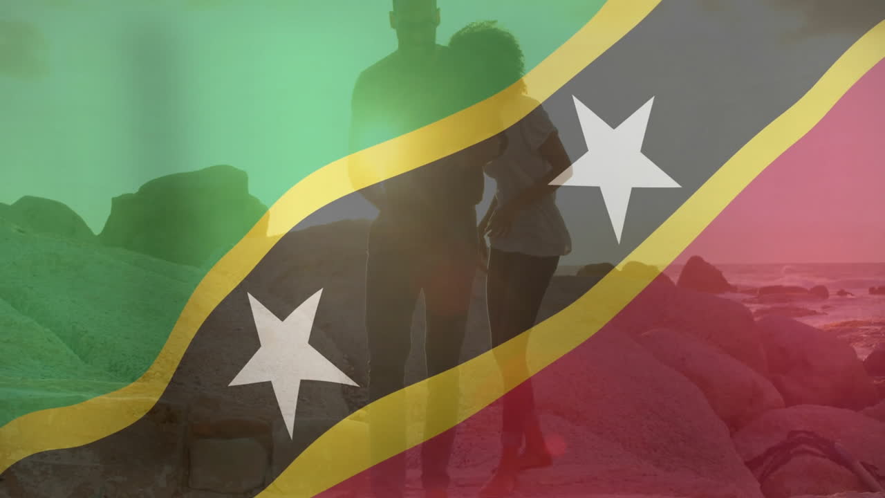 Standing on rocky beach, couple holding Saint Kitts and Nevis flag animation