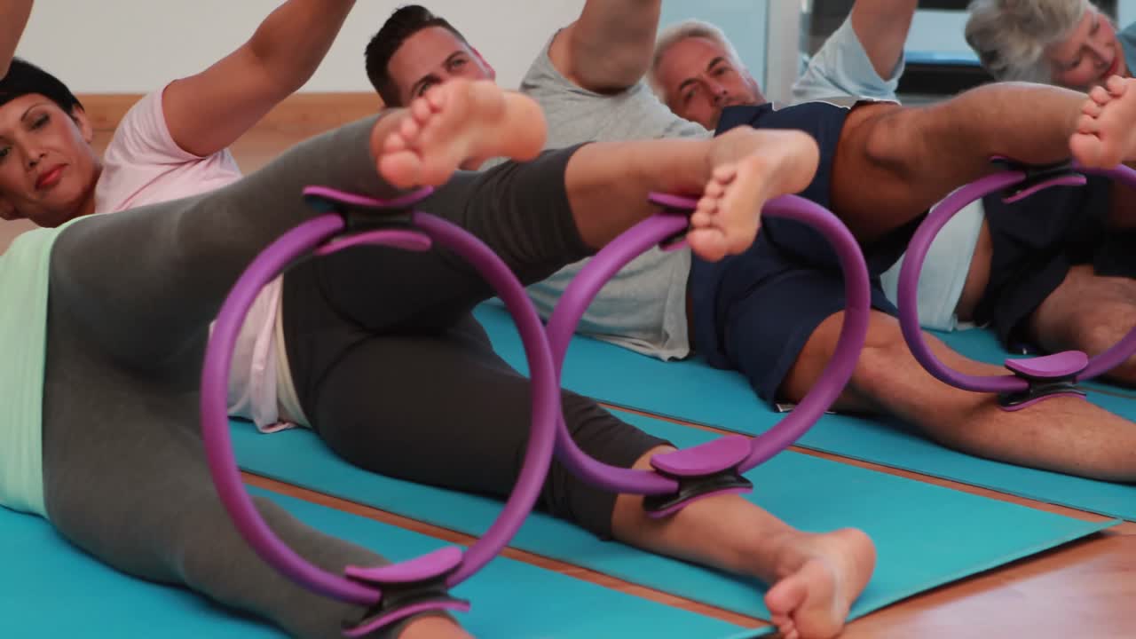 clase de pilates acostada usando anillos de pilates