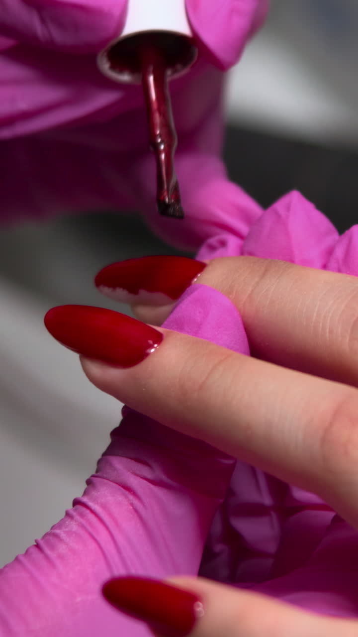 Manicurist Applying Red Nail Polish to Client's Finger