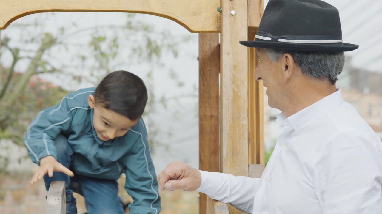 A tender and familiar scene where a grandfather gives his grandson ice cream in the backyard. The boy is playing in a wooden playhouse with a slide.