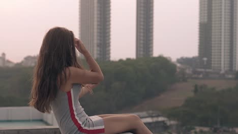 brunette sits on roof and takes selfie with black smartphone