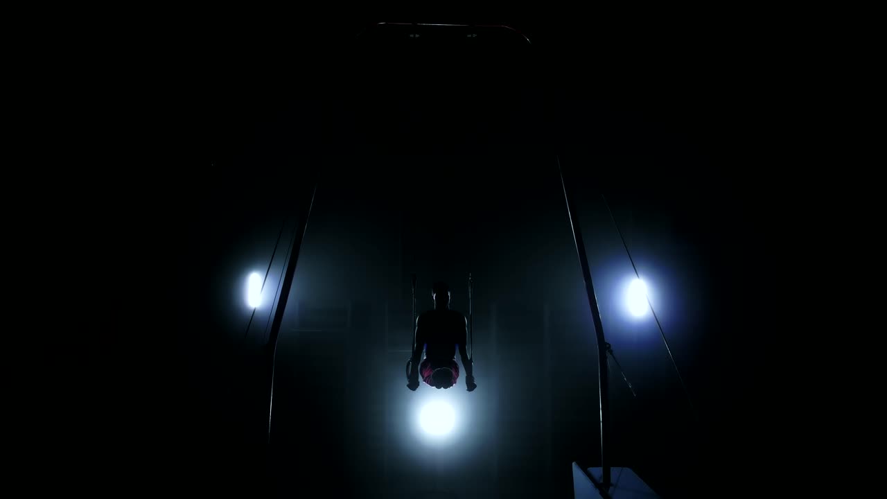 gimnasta en un fondo oscuro se para en sus manos usando anillos en el aire. realiza rotación en el programa olímpico en cámara lenta 120 fps. anillos de gimnasia, gimnasta profesional