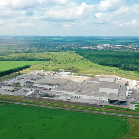 large industrial territory surrounded by nature. manufacturing near the road on beautiful green landscape. aerial view