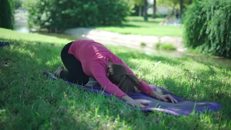 woman doing extended child and cobra asanas in park