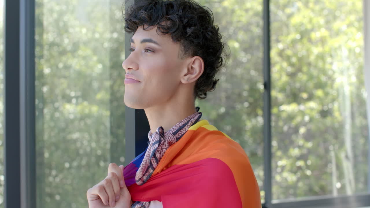 Wearing pride flag, person standing confidently and smiling at home