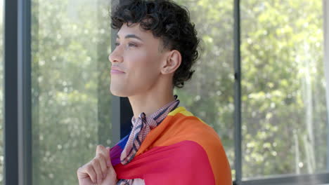 wearing pride flag, person standing confidently and smiling at home