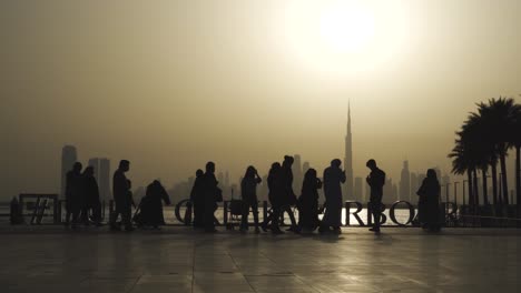 family of tourists visit dubai creek harbour overlooking famous dubai skyline at sunset in dubai, uae