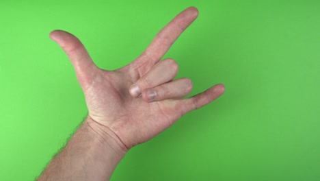 imágenes de una mano masculina que muestra un gesto de roca sobre un fondo verde