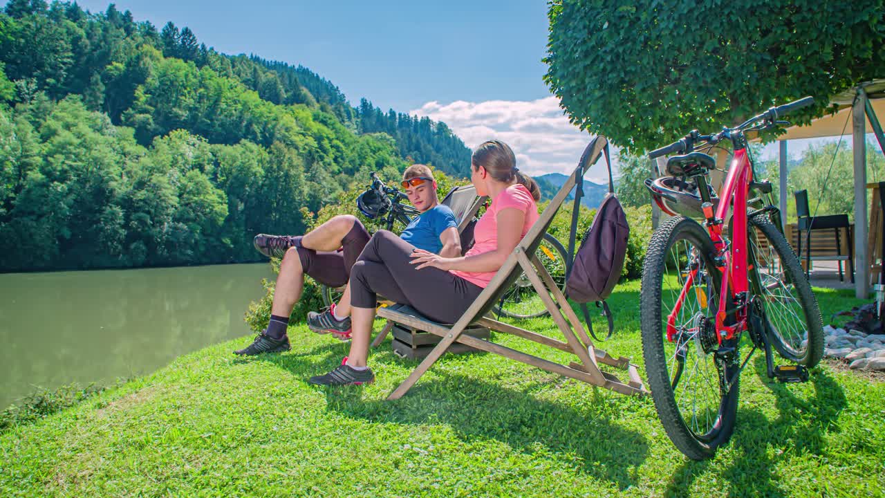 Lovers couple resting on green meadow by the river. Romantic relaxation