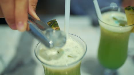 man throws ice to fresh juice in glass