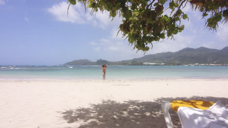 wide scenic view of latino lady return from swim in sea on tropical beach resort playa teco maimon, gentle zoom