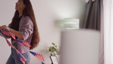 woman at home hanging up american stars and stripes flag bunting for party celebrating 4th july independence day 7