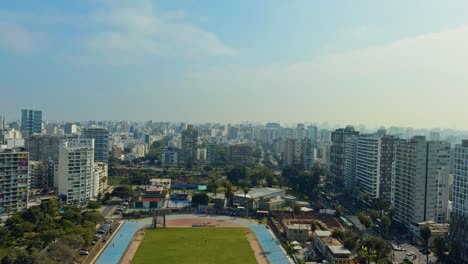 overhead establishing pan of city buildings with sunset glow casting across rooftops and trees, lima peru