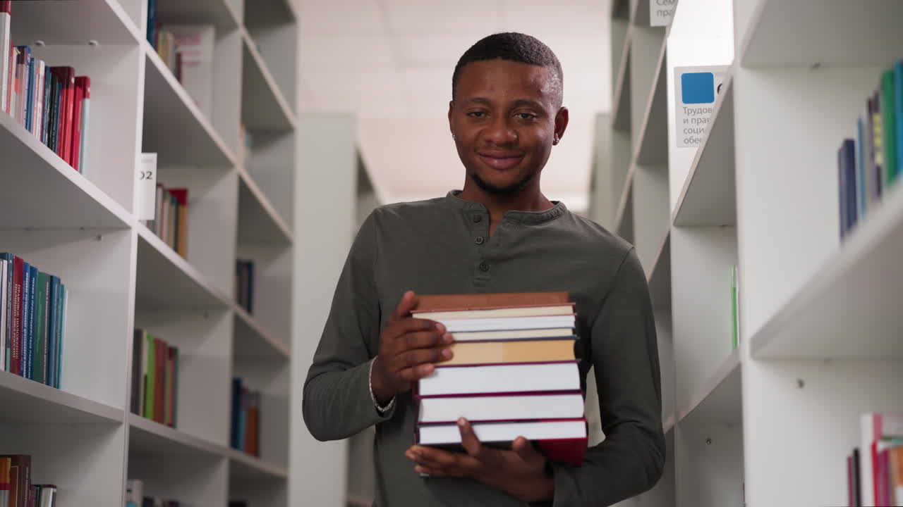 Positive teacher holds books in school library. African American student prepares literature stack to do homework in bookstore. Black guy with folios