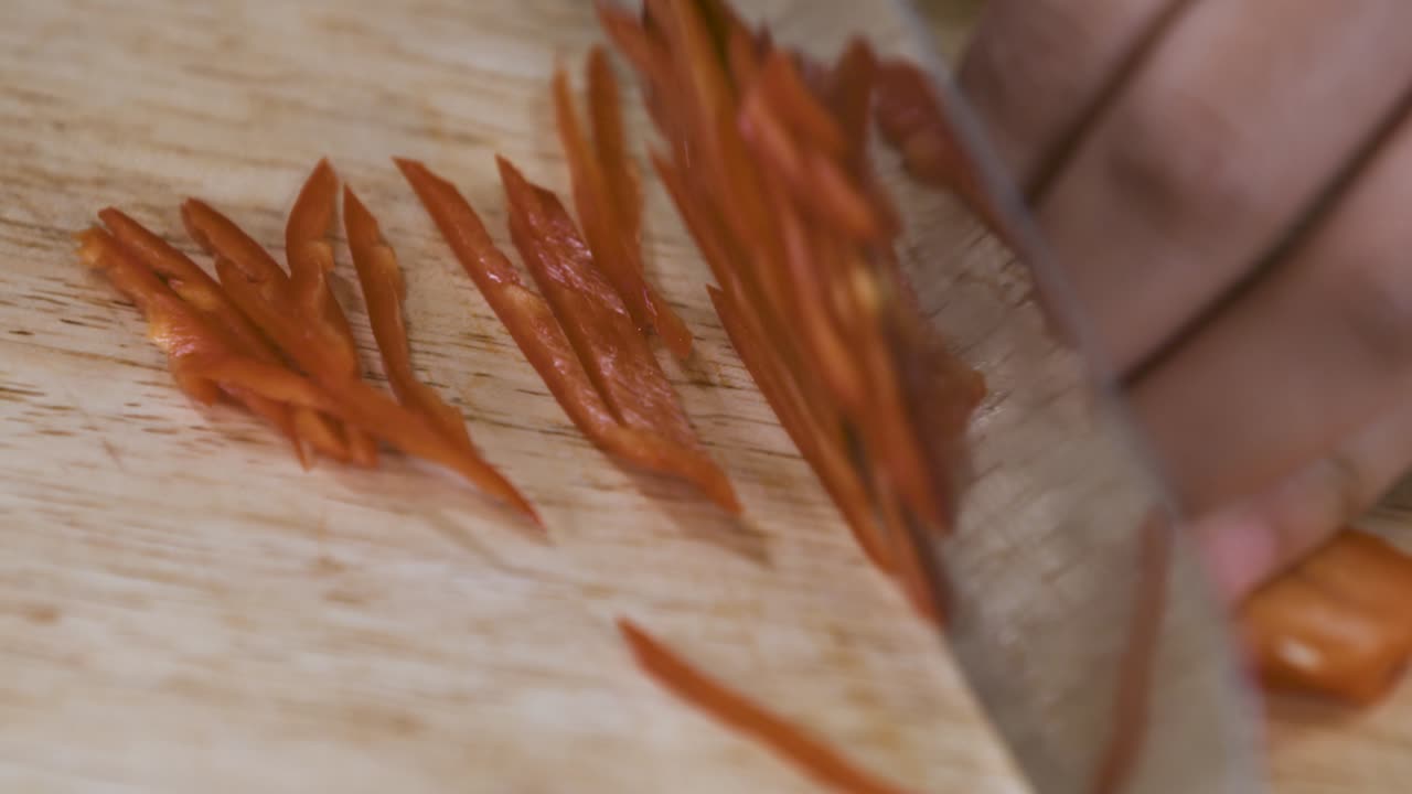 매콤한 붉은 고추를 나무 커팅 보드에 얇은 조각으로 자른다 - 가까이