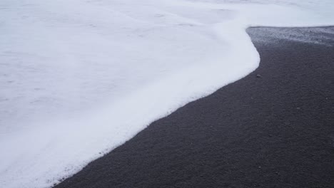 Gentle-waves-over-black-sand-at-a-beach-in-Iceland---Slow-motion