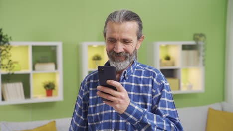 Smiling-old-man-having-a-pleasant-and-fun-time-on-smartphone.