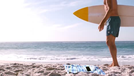 surfista sonriente usando su teléfono inteligente antes de entrar en el agua