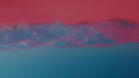 Blau-Gefärbtes-Wasser,-Das-Wellen-Auf-Rotem-Hintergrund-Schlägt
