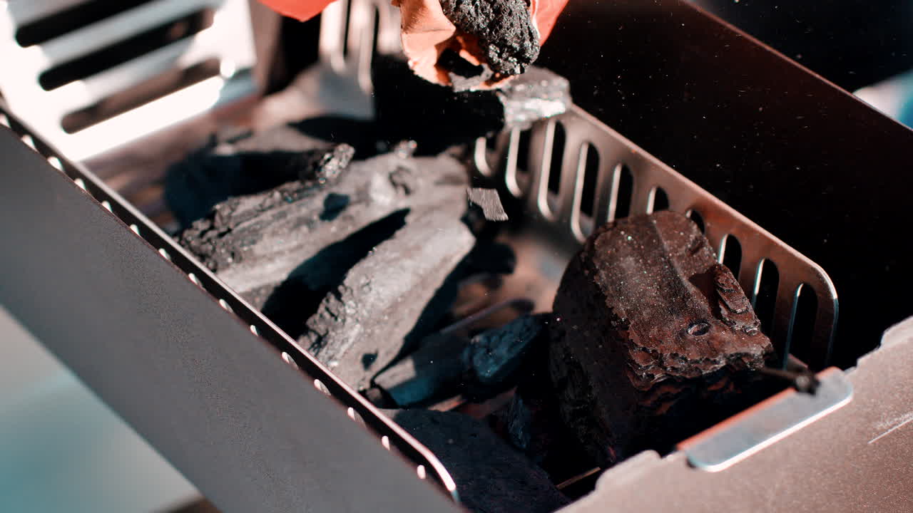 Filling a small grill with charcoal directly from the bag