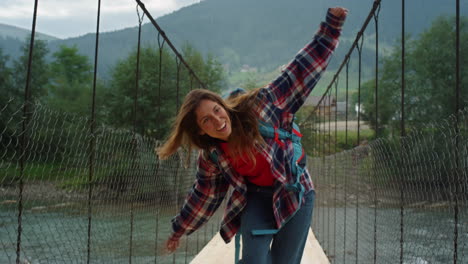 Smiling-girl-hiking-woods-on-mountain-river-bridge.-Traveler-have-fun-outdoors.