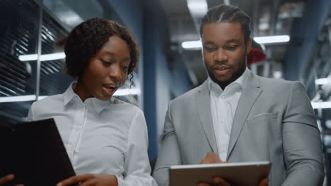 positive afro business couple discussing plan on tablet