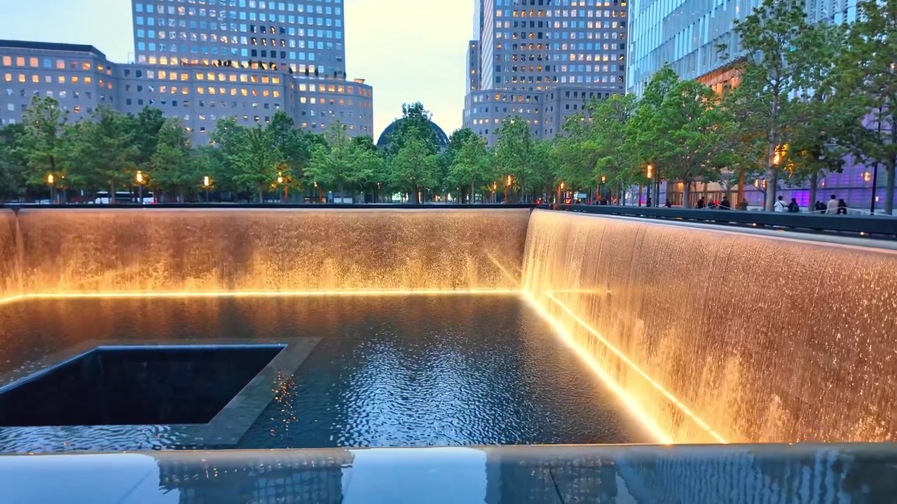 Nueva York, EE. UU., 5 de junio de 2026: Estanque reflectante en el Monumento del 11 de Septiembre, Ciudad de Nueva York, Nueva York. Cascada que desciende a un vacío cuadrado bajo torres iluminadas y árboles verdes al anochecer.