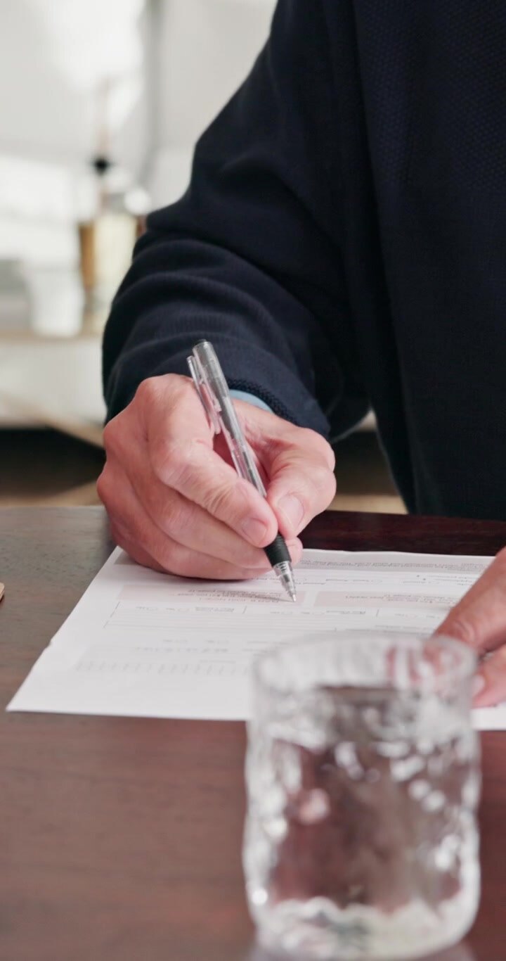 Ældre mand underskriver ansøgning om pensionering med hjælp