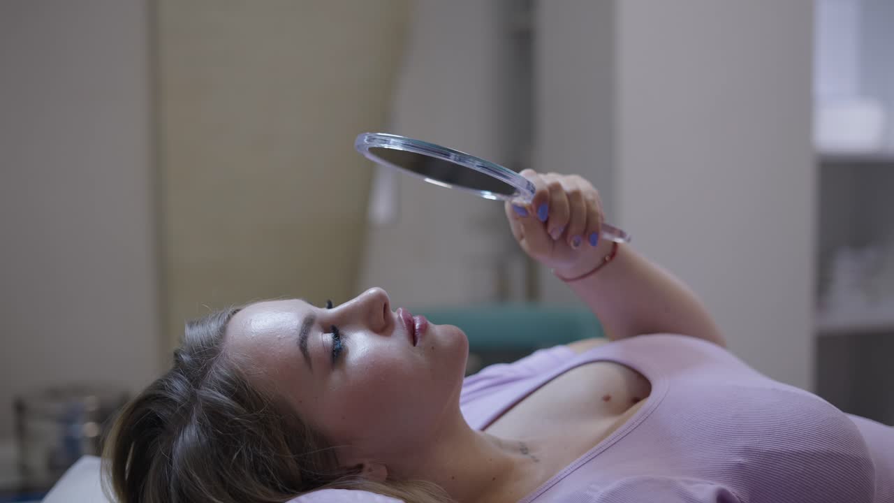 Woman examining her face with a mirror in a beauty salon or clinic