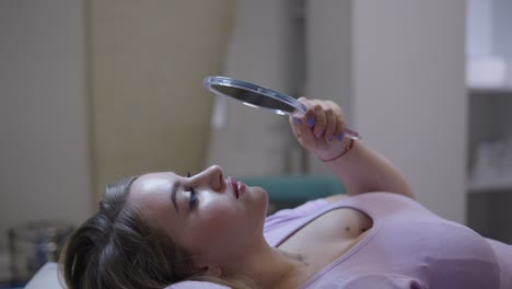woman examining her face with a mirror in a beauty salon or clinic