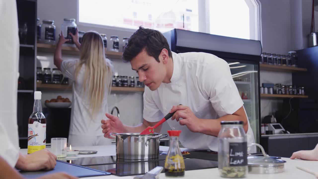 cocinero caucásico vestido con ropa blanca en la cocina de un restaurante preparando comida