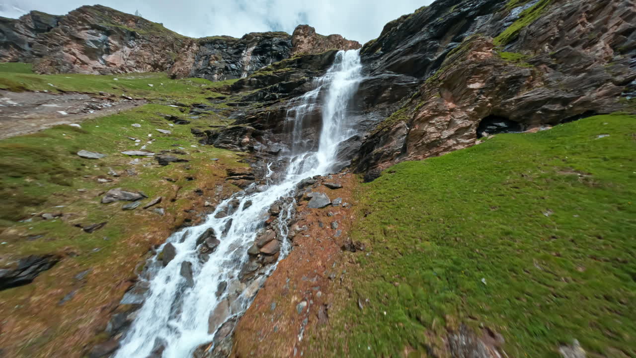 una hermosa cascada cae por una ladera rocosa cerca de cervinia en un día nublado
