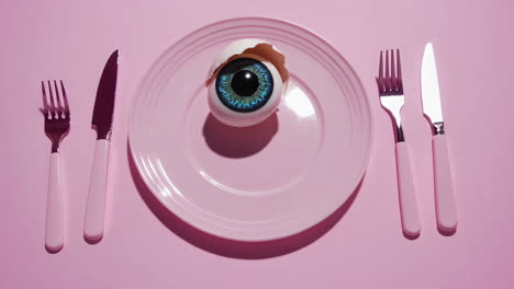 surreal eyeball in a cracked egg on a pink plate
