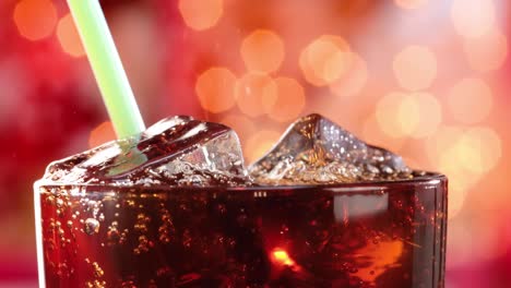 Cola-Und-Trinkschlauch-Mit-Eis-Und-Blasen-Im-Glas-Auf-Verschwommenem-Licht,-Verschwommenem-Hintergrund.