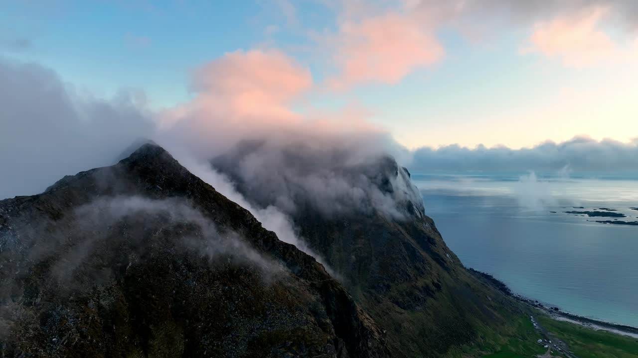 Midnight aerial of Mannen and coastal peaks wrapped in fog between Utakleiv and Haukland in Lofoten