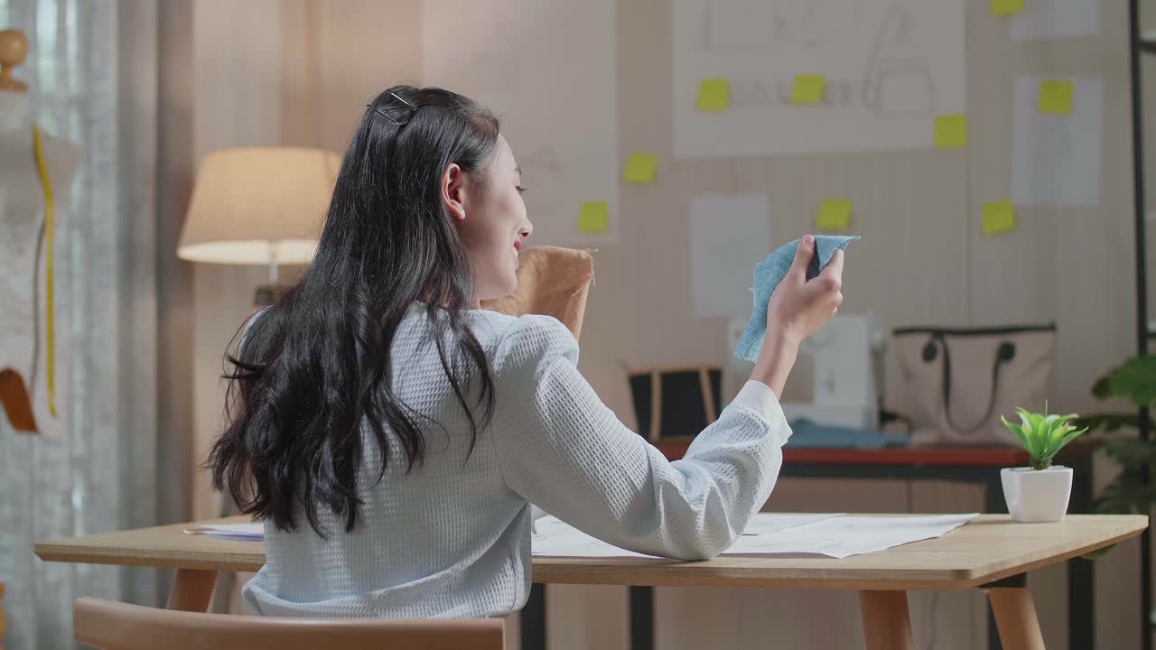 손에 있는 직물을 바라보는 레이아웃 본드와 함께 여성 가방 디자이너의 뒷면