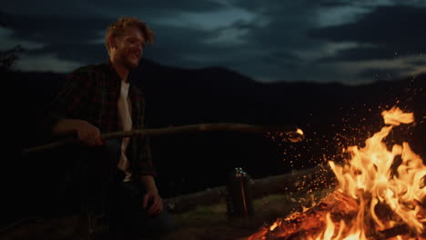 joyful man camping outside on dark evening. mountains traveler relax on nature.