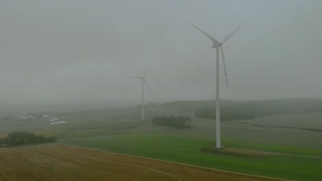 Aerial-footage-close-up-to-wind-farm,-windmill-during-fog,-grey-landscape-around,-renewable-energy-in-the-open-field,-below-natural-landscape,-green-energy-is-important