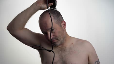 man facing camera while he uses clippers to cut his own hair