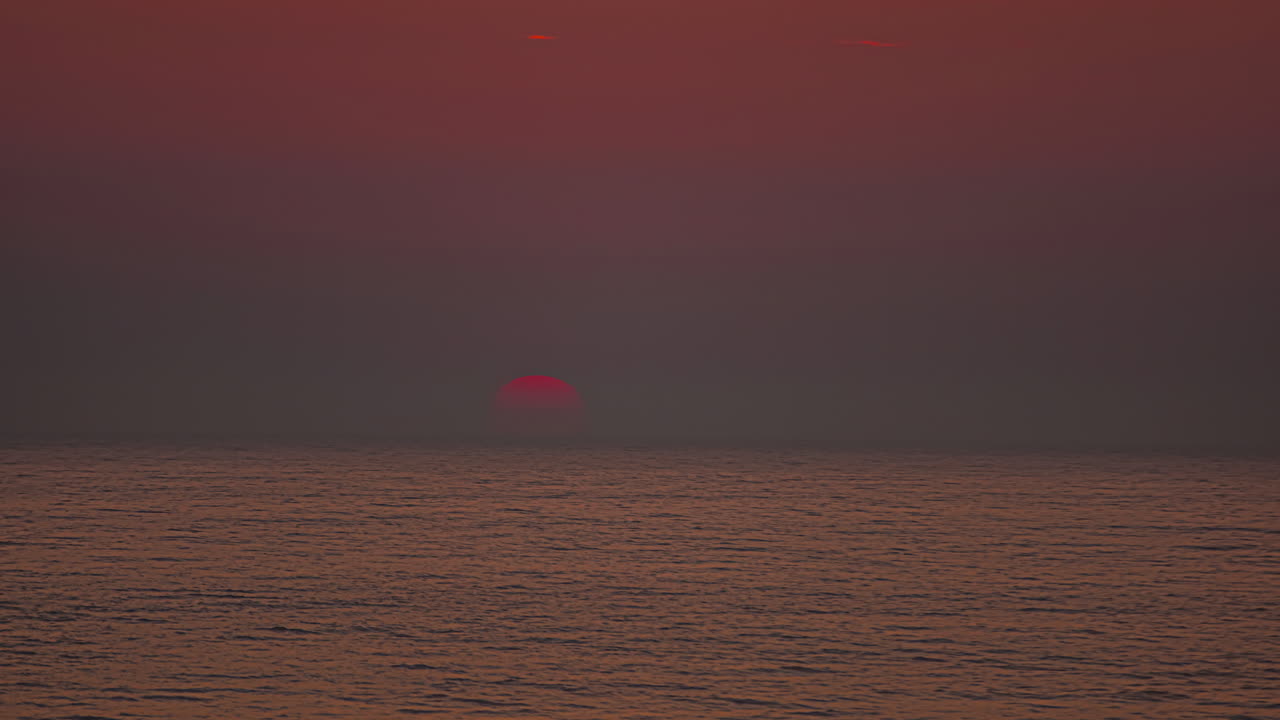 일출 때 바다 위로 떠오르는 밝은 오렌지색 태양