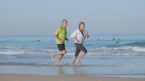 woman running ahead her husband while they jogging on beach