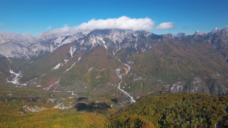 autumn colors in the stunning alpine valley surrounded by high mountains under clouds and blue clear sky